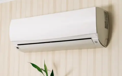 Un aire acondicionado blanco montado en una pared con papel tapiz. Averigua cuanto consume un aire acondicionado para ahorrar energía.