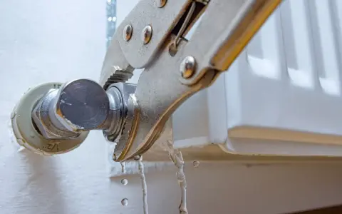Herramienta sujeta el grifo de un radiador que gotea. Se está intentando cambiar la llave radiador que gotea.