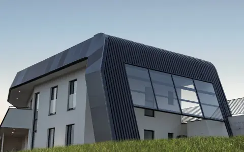 Moderna casa autosuficiente con techo curvo y grandes ventanales, rodeada de hierba alta bajo un cielo despejado.