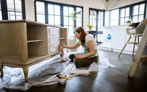 Mujer aplicando una capa de pintura a un mueble antiguo.