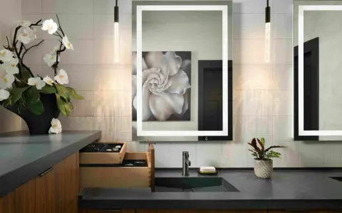 Elegante tocador con espejo iluminado, lavabo empotrado y orquídeas. Ideal para calcular el precio reforma baño 4 m2.