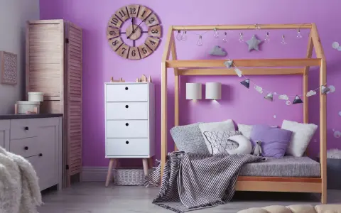Adolescentes pintan habitación juvenil. Un espacio lleno de color lila, con cama de madera, cómoda blanca y decoración infantil.