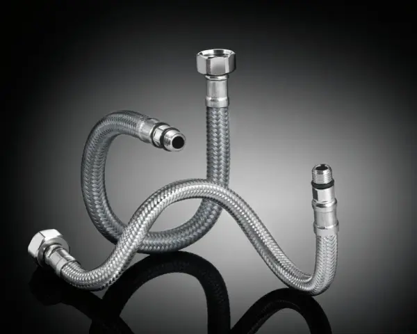 Tres latiguillos de grifo de acero inoxidable trenzado, con diferentes medidas y conexiones, sobre fondo oscuro.