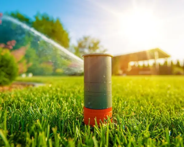 Aspersor de césped en acción, mostrando diferentes tipos de aspersores para riego eficiente bajo el sol.