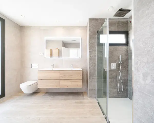 Baño moderno con ducha de cristal, lavabo flotante y WC suspendido. La fontanería se integra con estilo, cuidando cada altura y medida.