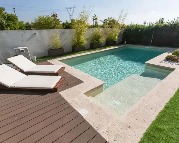 Modern pool with deck, lounge chairs, and bamboo plants. Great ideas para decorar alrededor de la piscina para un oasis de verano.