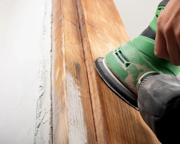 Lijando madera para quitar barniz viejo. El proceso de como quitar barniz de la madera se ve en acción con una lijadora.
