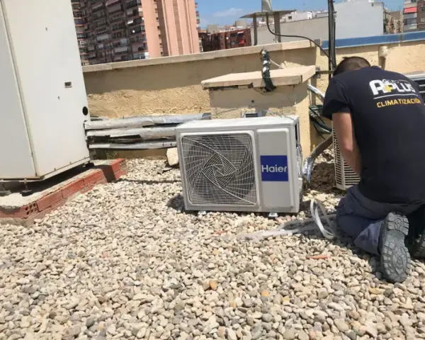 Técnico realizando mantenimiento de aire acondicionado en una azotea. Se ve una unidad Haier y otras unidades de climatización.