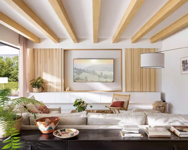 Salón moderno con palilleria en pared, vigas de madera en techo y sofá modular.