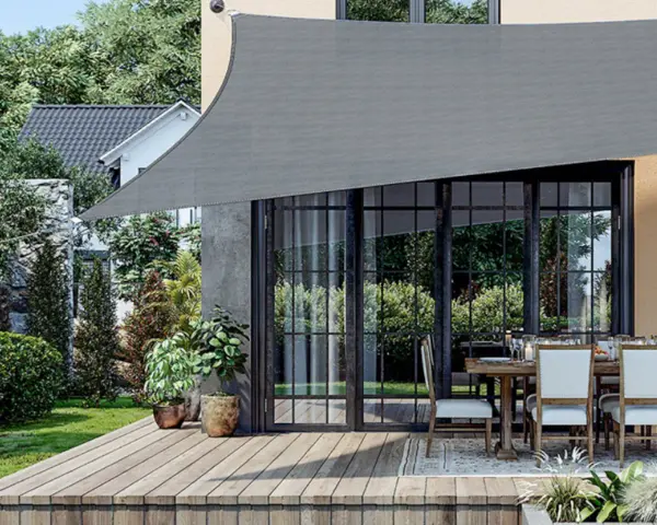 Un toldo gris protege un patio con mesa y sillas. Muestra varios tipos de toldos para exteriores, ideales para crear sombra.
