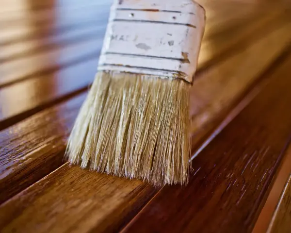 Brocha aplicando barniz a madera. Diferentes tipos de barniz para madera protegen y embellecen.