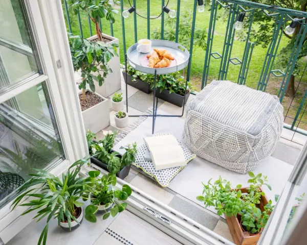 Acogedor rincón en unas terrazas pequeñas con encanto: cojines, plantas, un libro y cruasanes para un desayuno perfecto.