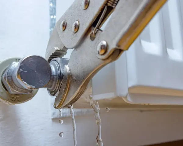 Herramienta sujeta el grifo de un radiador que gotea. Se está intentando cambiar la llave radiador que gotea.