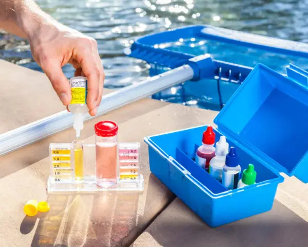 Persona usa un kit para medir el cloro y el pH de la piscina. Se puede echar cloro a una piscina de sal.