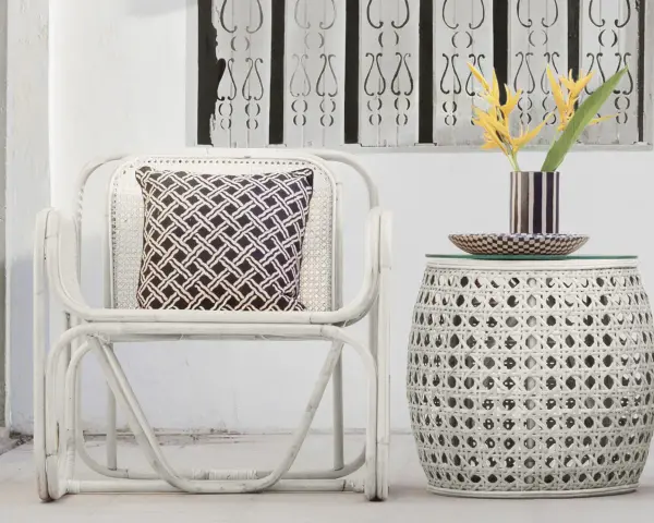 Sillón y mesa auxiliar de mimbre blanco, con cojín estampado y flores amarillas. Ideas de colores para pintar mimbre.