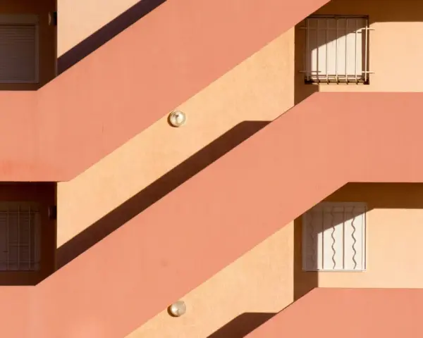 Fachada con escaleras y ventanas, sombras marcadas. Un ejemplo de cómo impermeabilizar pared exterior para protegerla.