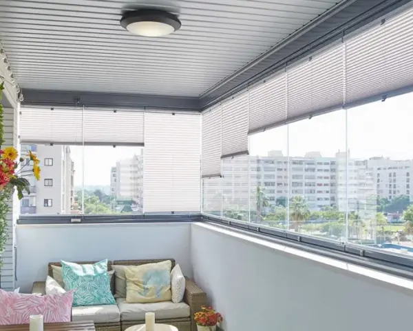 Ideas para tapar balcón: un espacio acogedor con sofá, plantas y vistas urbanas.