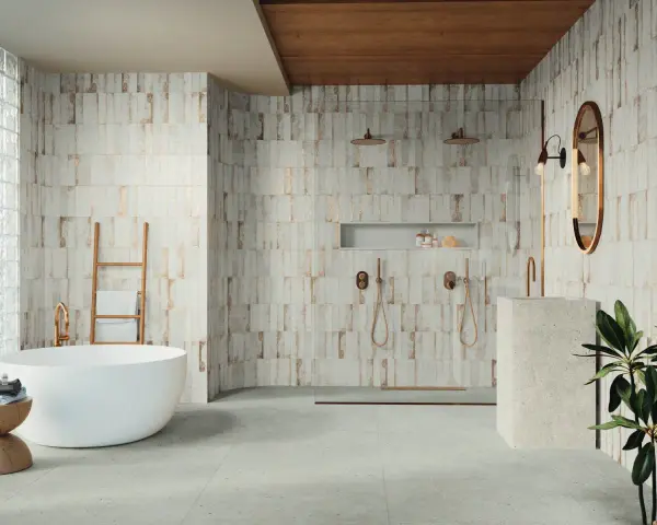Baño moderno con bañera exenta y ducha doble. Las paredes presentan azulejos con un diseño rústico y detalles dorados, reflejando las últimas tendencias azulejos baño.