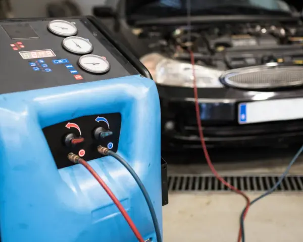 Máquina para cargar gas aire acondicionado conectada a un coche.