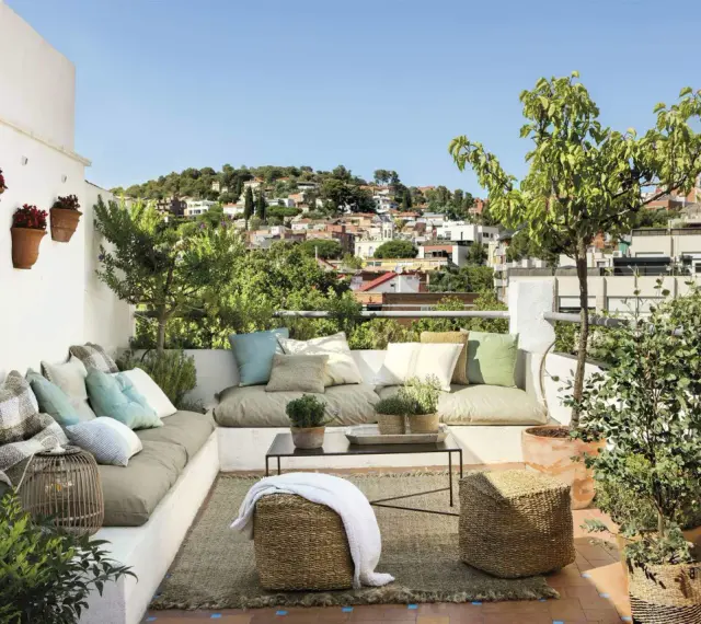 Un espacio perfecto para **chill out** en la **terraza**, con cómodos cojines, plantas y vistas a la ciudad.