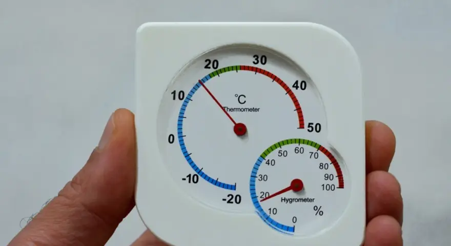 Termómetro y higrómetro en mano, mostrando cómo medir la humedad en casa.