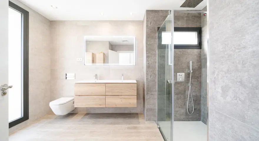 Baño moderno con ducha de cristal, lavabo flotante y WC suspendido. La fontanería se integra con estilo, cuidando cada altura y medida.
