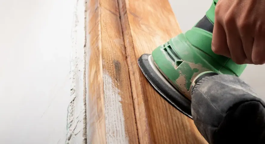 Lijando madera para quitar barniz viejo. El proceso de como quitar barniz de la madera se ve en acción con una lijadora.