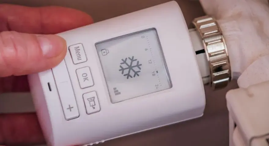 Termostato digital para sistemas de calefacción, con pantalla que muestra un copo de nieve y botones para ajustar la temperatura.