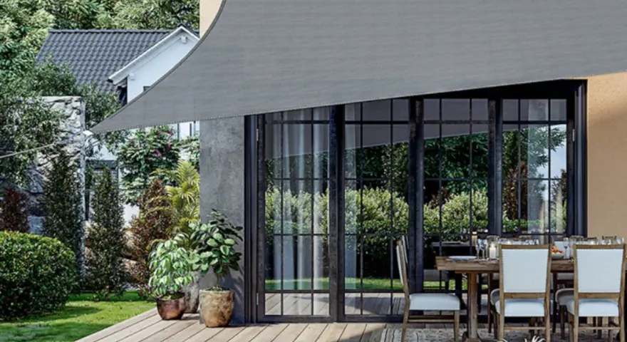 Un toldo gris protege un patio con mesa y sillas. Muestra varios tipos de toldos para exteriores, ideales para crear sombra.
