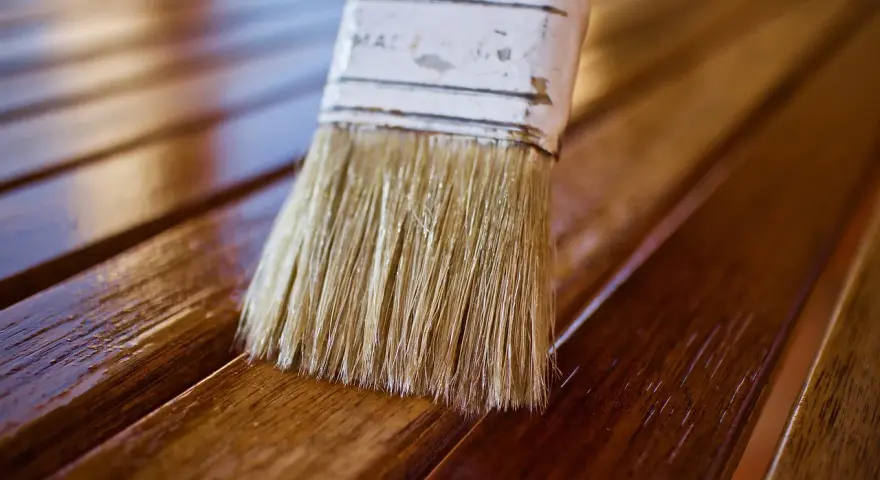 Brocha aplicando barniz a madera. Diferentes tipos de barniz para madera protegen y embellecen.