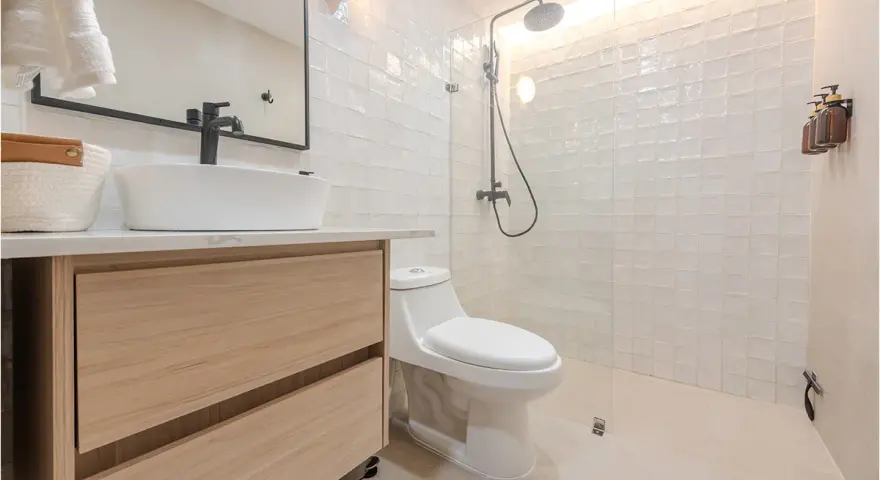 Baño moderno con lavabo sobre mueble de madera, inodoro y ducha con azulejos blancos. ¡Un proyecto de pintar azulejos baño que inspira!