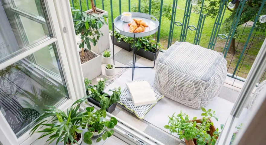 Acogedor rincón en unas terrazas pequeñas con encanto: cojines, plantas, un libro y cruasanes para un desayuno perfecto.