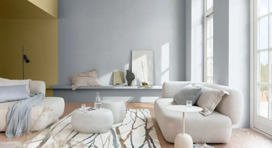 Salón moderno con sofás blancos, alfombra de ramas y paredes en pintura al agua gris y ocre.