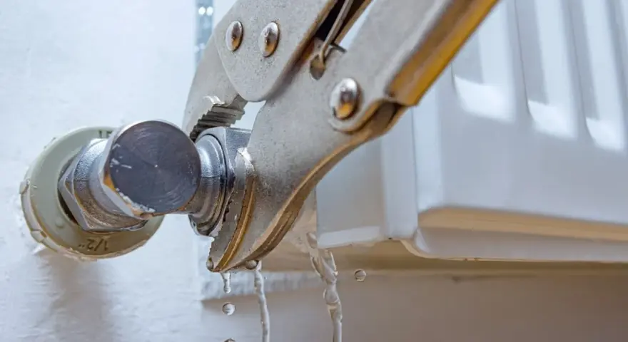 Herramienta sujeta el grifo de un radiador que gotea. Se está intentando cambiar la llave radiador que gotea.