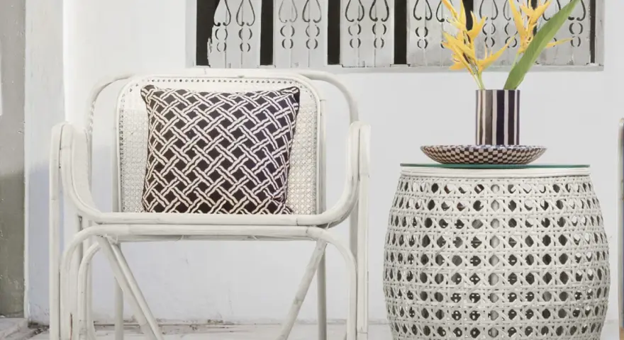 Sillón y mesa auxiliar de mimbre blanco, con cojín estampado y flores amarillas. Ideas de colores para pintar mimbre.