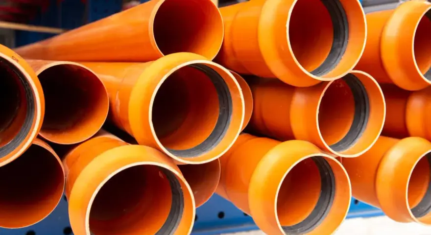 Tubos de PVC naranja apilados, listos para ser instalados en exteriores. Perfectos para proyectos de fontanería y drenaje.