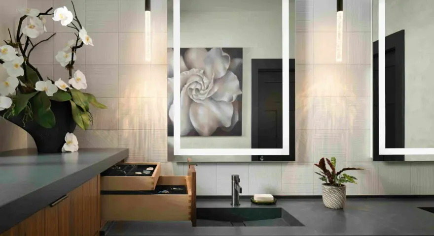 Elegante tocador con espejo iluminado, lavabo empotrado y orquídeas. Ideal para calcular el precio reforma baño 4 m2.