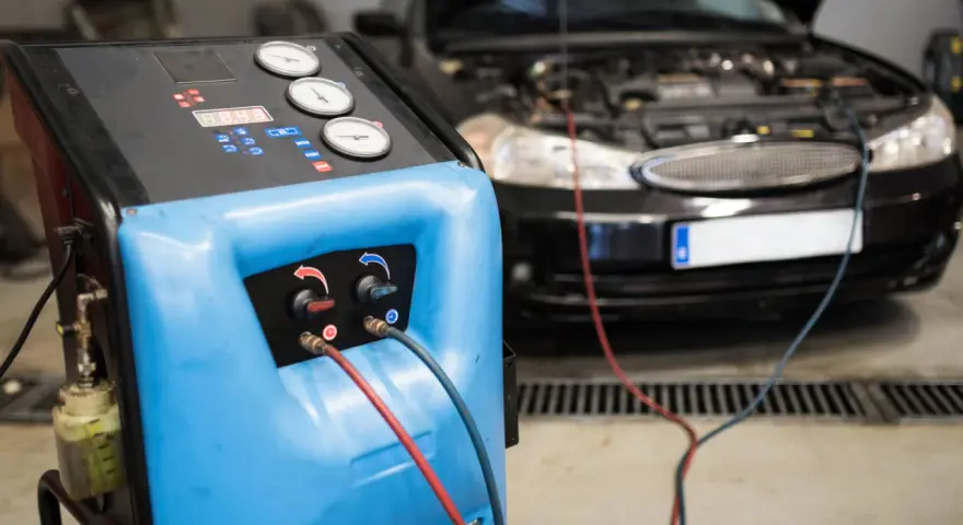 Máquina para cargar gas aire acondicionado conectada a un coche.
