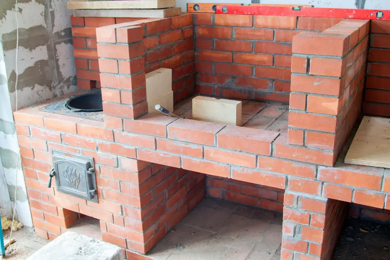 Construcci&oacute;n de una chimenea de obra. Ladrillos rojos, nivel y herramientas listas para empezar.