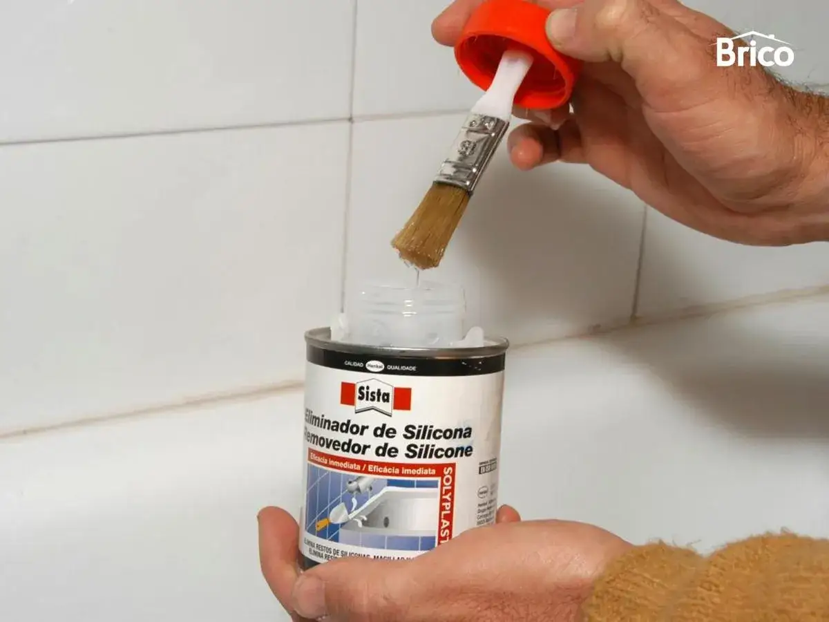 Mano aplica producto para quitar silicona de ba&ntilde;era con brocha.
