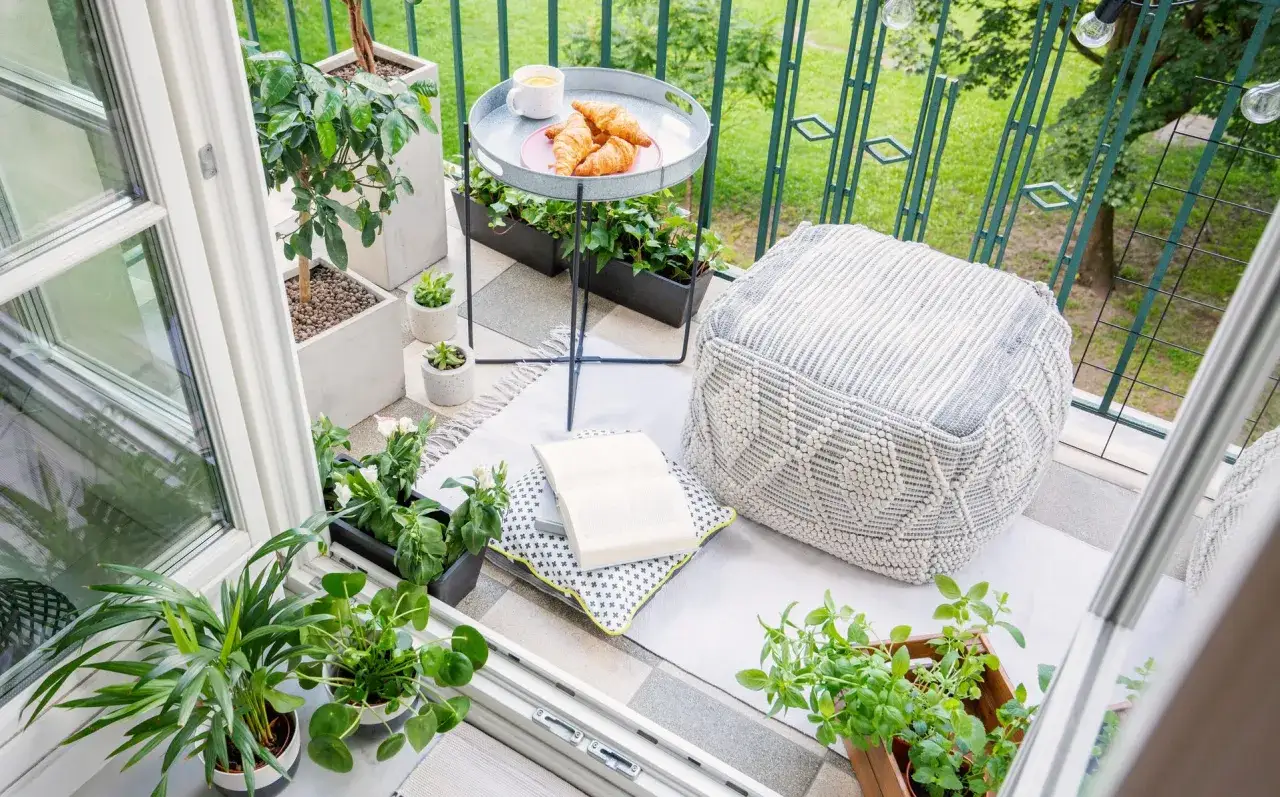 Acogedor rinc&oacute;n en terrazas peque&ntilde;as con encanto: coj&iacute;n, libro, caf&eacute; y cruasanes invitan a relajarse entre plantas.