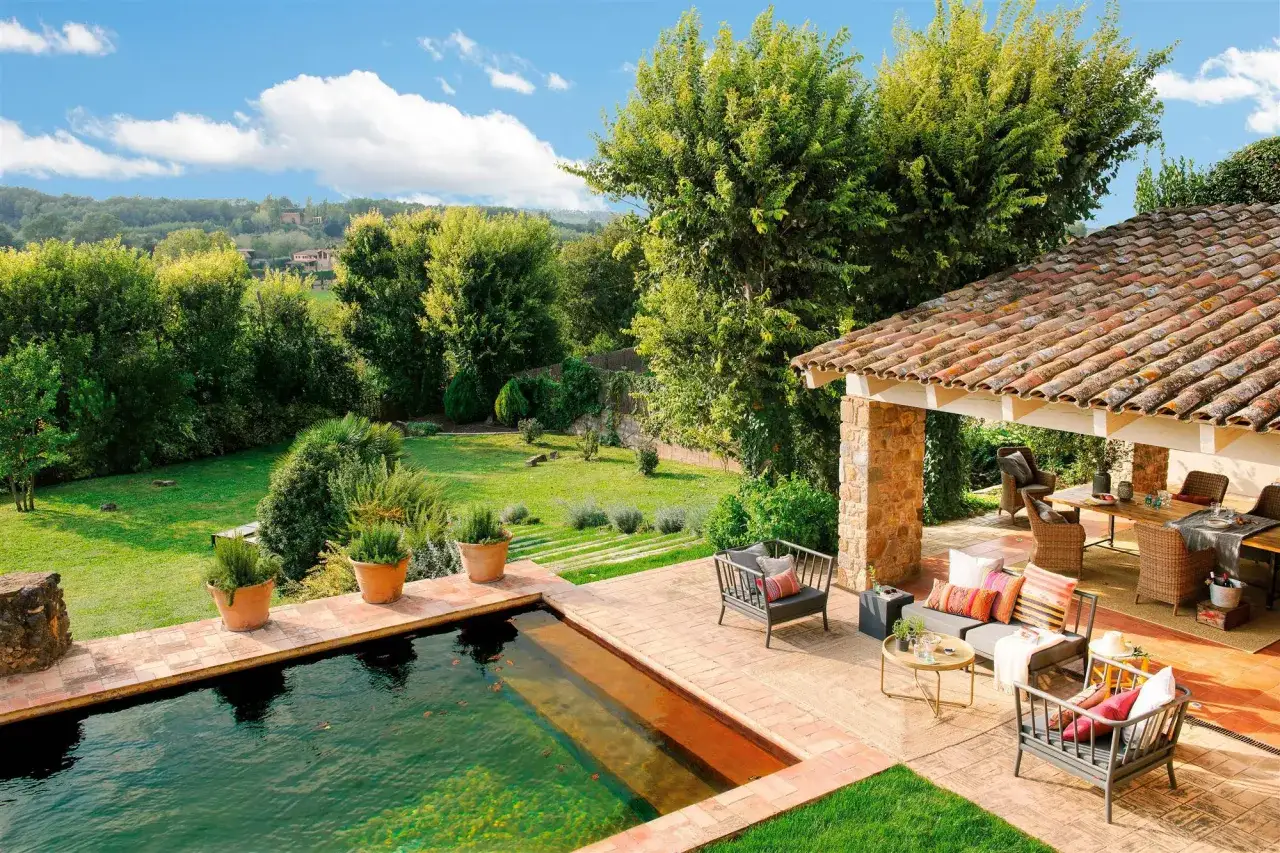 Ideas para decorar alrededor de la piscina: zona de estar, comedor exterior y plantas en macetas crean un oasis acogedor.