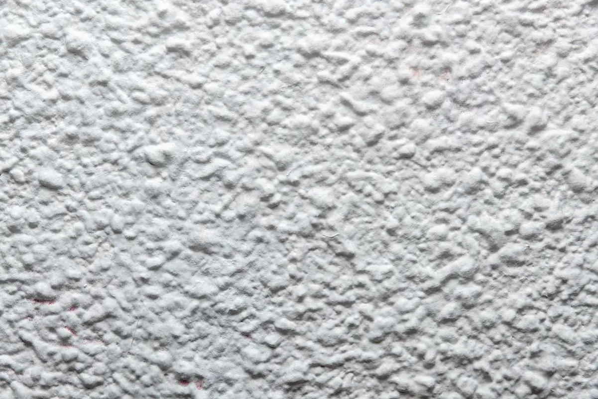 Textura de pared blanca con relieve, como si se estuviera empezando a quitar gotele con agua.
