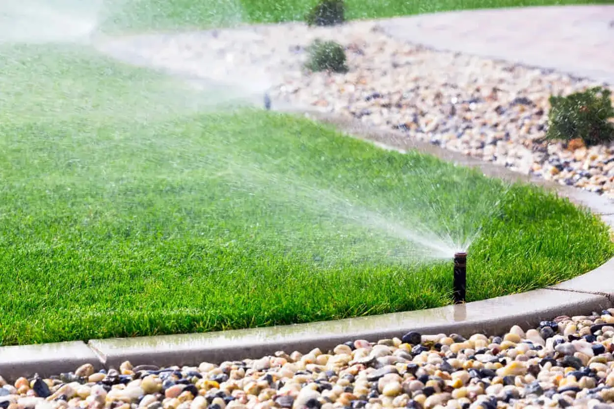 Aspersor de riego automático regando césped verde. Varios tipos de aspersores son esenciales para mantener jardines saludables.