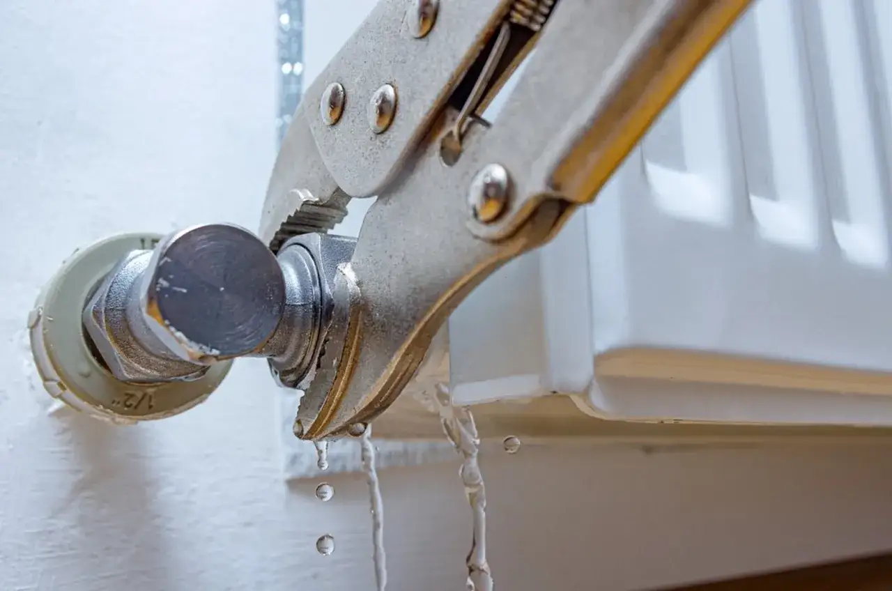 Herramienta sujetando una conexión de radiador que gotea. Se está intentando cambiar la llave radiador que gotea.