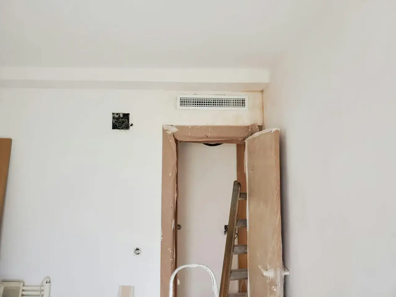 Habitaci&oacute;n en obra con preinstalaci&oacute;n de aire acondicionado visible en la pared. Una escalera de madera est&aacute; apoyada en el marco de una puerta.