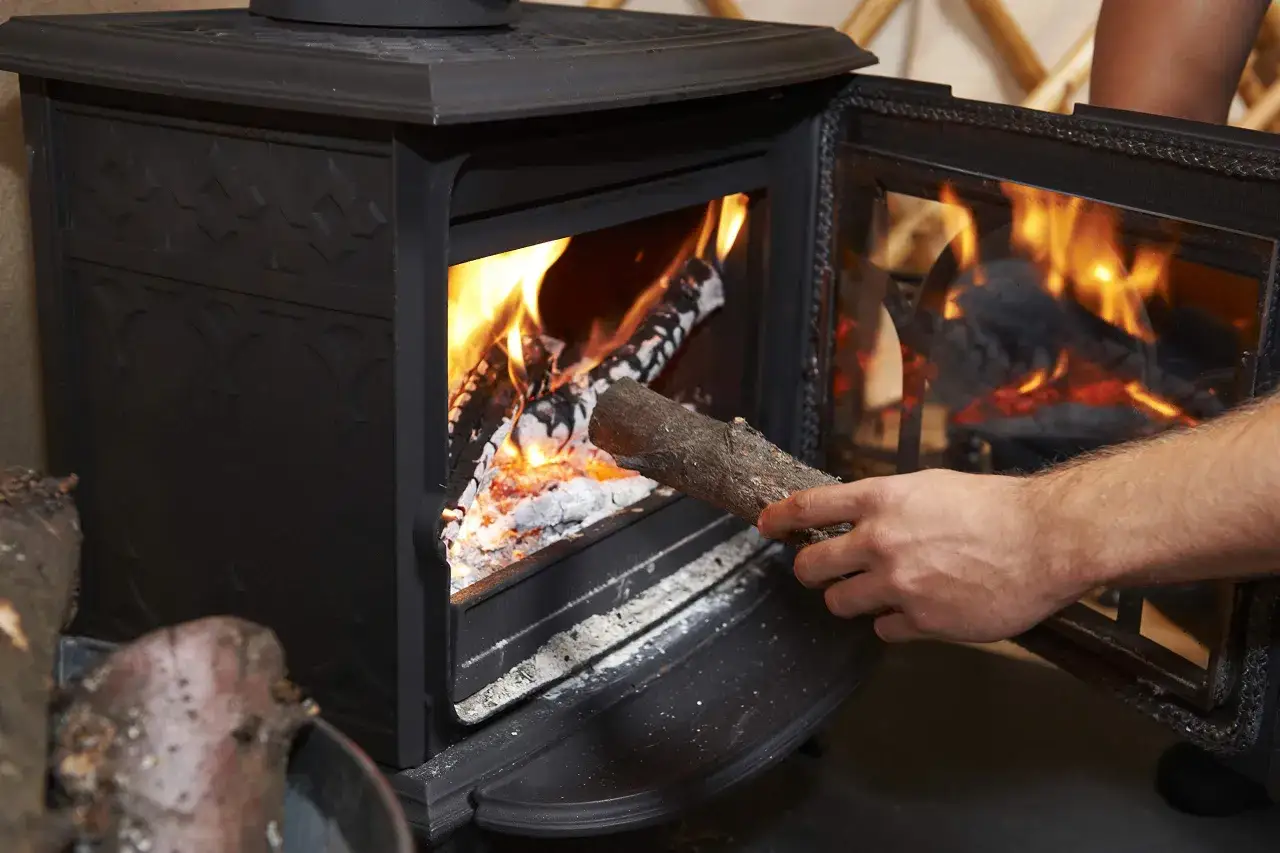 Mano a&ntilde;ade le&ntilde;a a una chimenea encendida. La pregunta es: &iquest;cu&aacute;l es la mejor le&ntilde;a para chimenea?