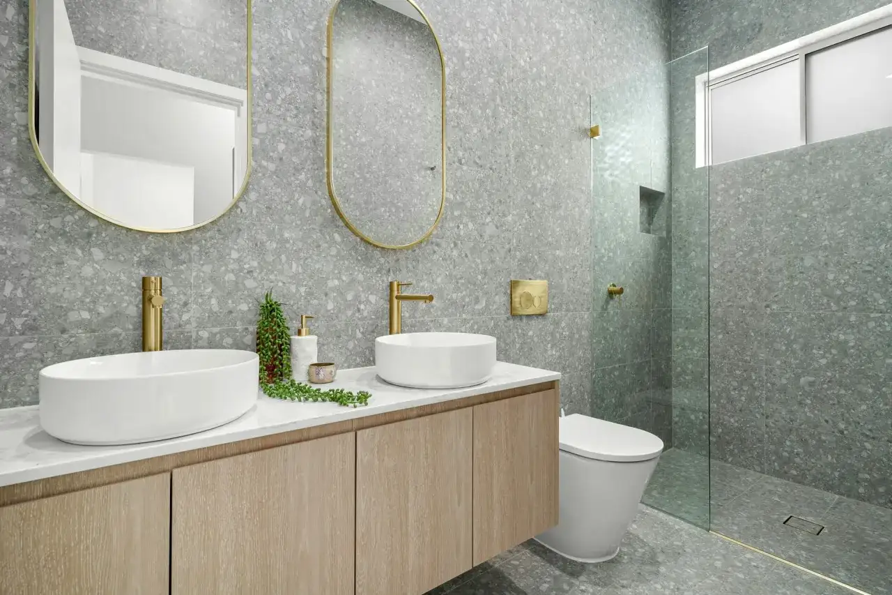 Modernos ideas baños con lavabos sobre encimera, grifería dorada y azulejos de terrazo gris. Ducha con mampara de cristal.