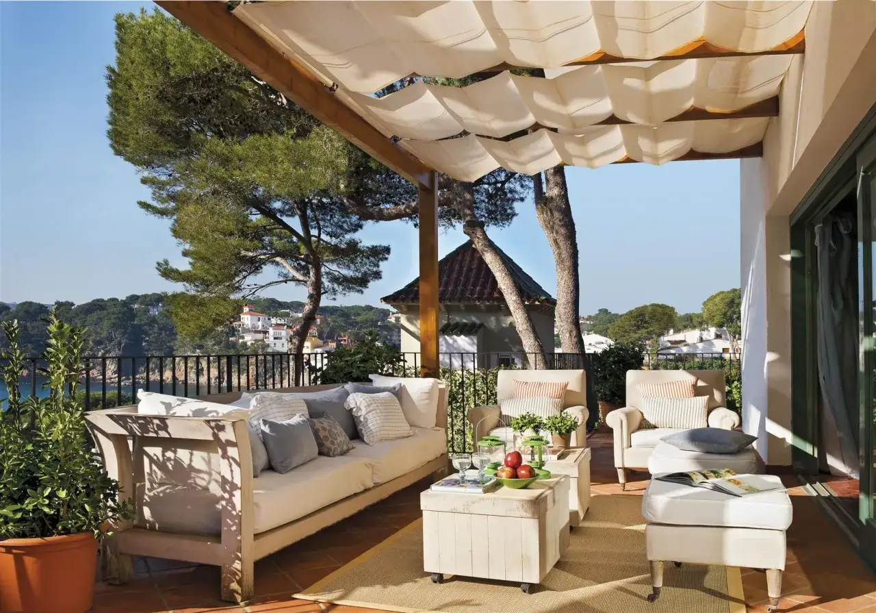 Acogedora terraza &aacute;tico con sof&aacute;, sillones y mesa auxiliar, ideal para disfrutar de las vistas al mar y la vegetaci&oacute;n.