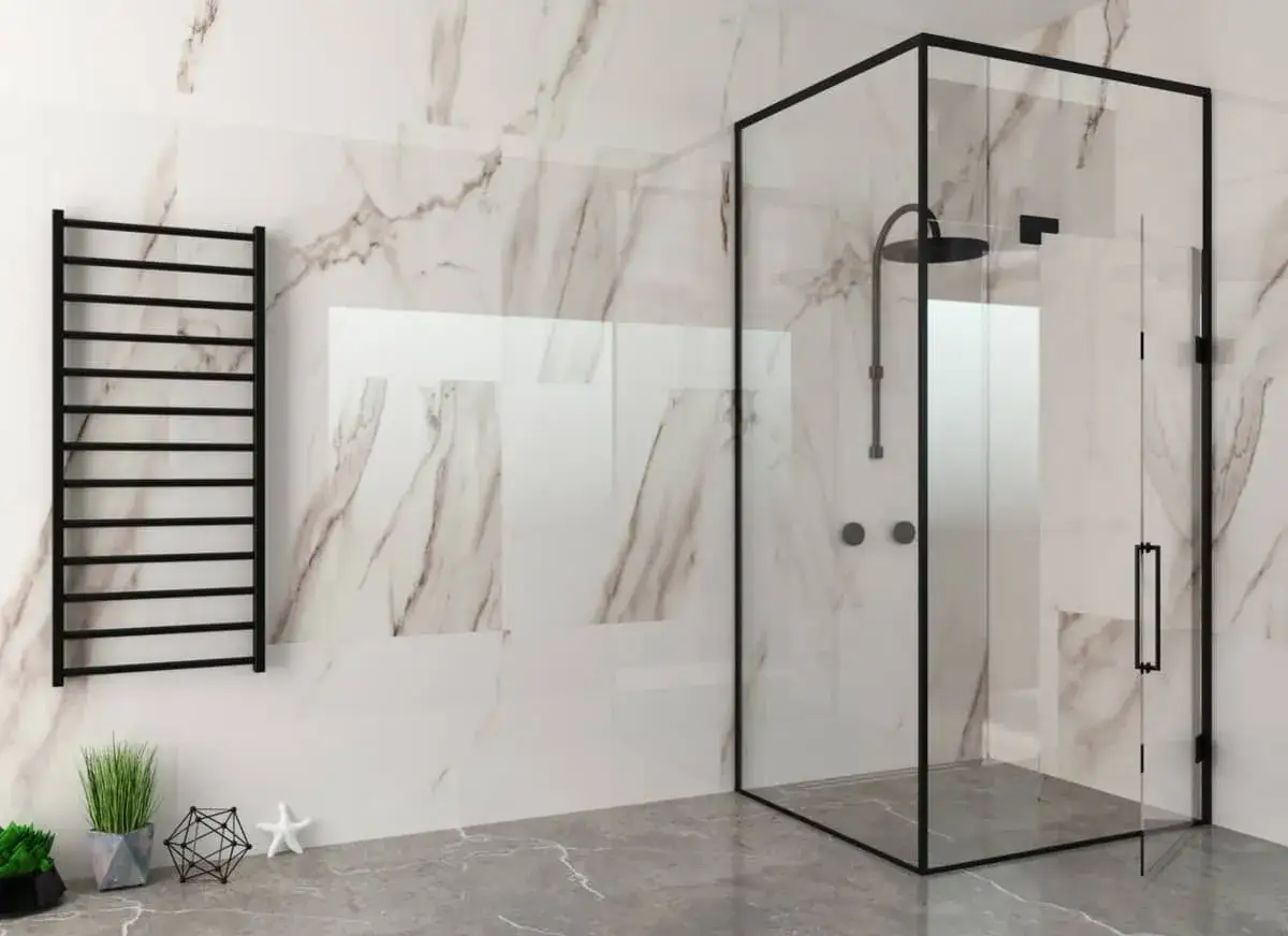 Moderno ba&ntilde;o con mampara de ducha de esquina negra, toallero y azulejos de m&aacute;rmol.